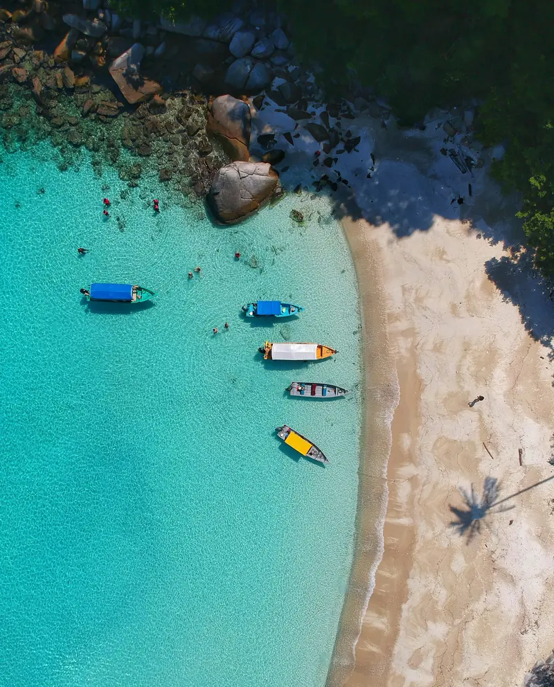 Boats on turquoise water beside a white sand beach in the Cayman Islands